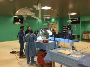 Photograph of a group of people around an operating table.